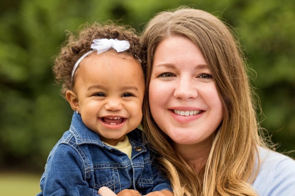 Smiling woman and little girl with bow.